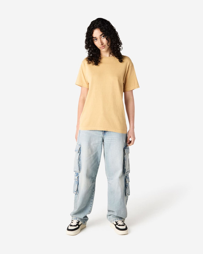 A unisex heavyweight cotton t-shirt in mustard yellow, paired with light blue cargo trousers.