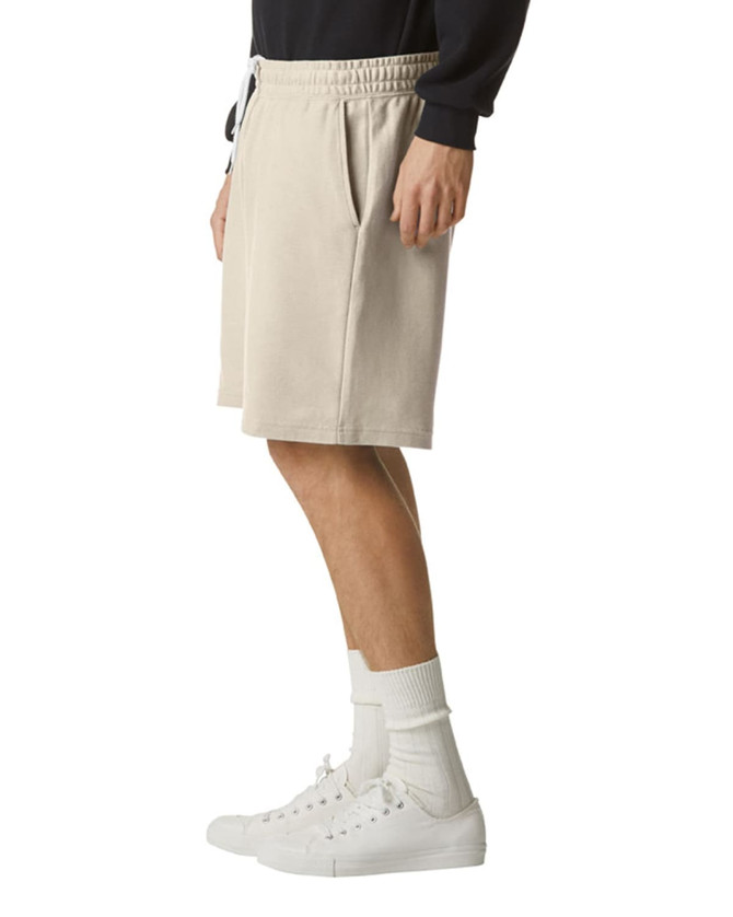 Beige unisex gym shorts with an elastic waistband and pockets, featuring a logo on the side.
