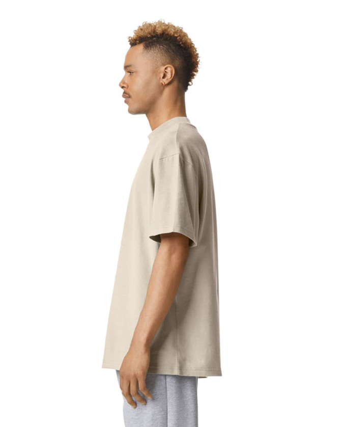 A unisex mockneck t-shirt in a neutral beige colour, displayed from the side, featuring a simple design and logo.