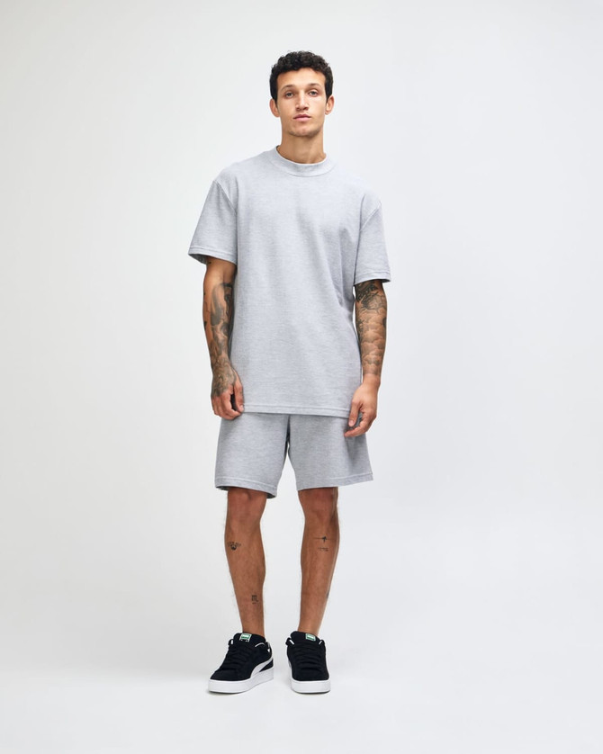 A grey unisex pique mockneck T-shirt with short sleeves and a standard fit. It features a logo on the garment.
