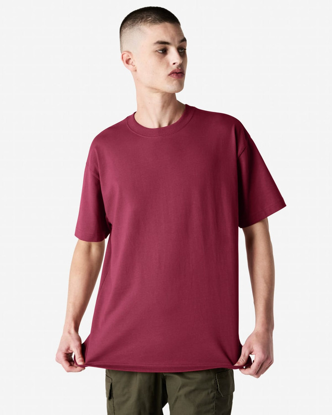 A maroon heavyweight t-shirt on a model, featuring a rounded neckline and short sleeves, with a logo present.