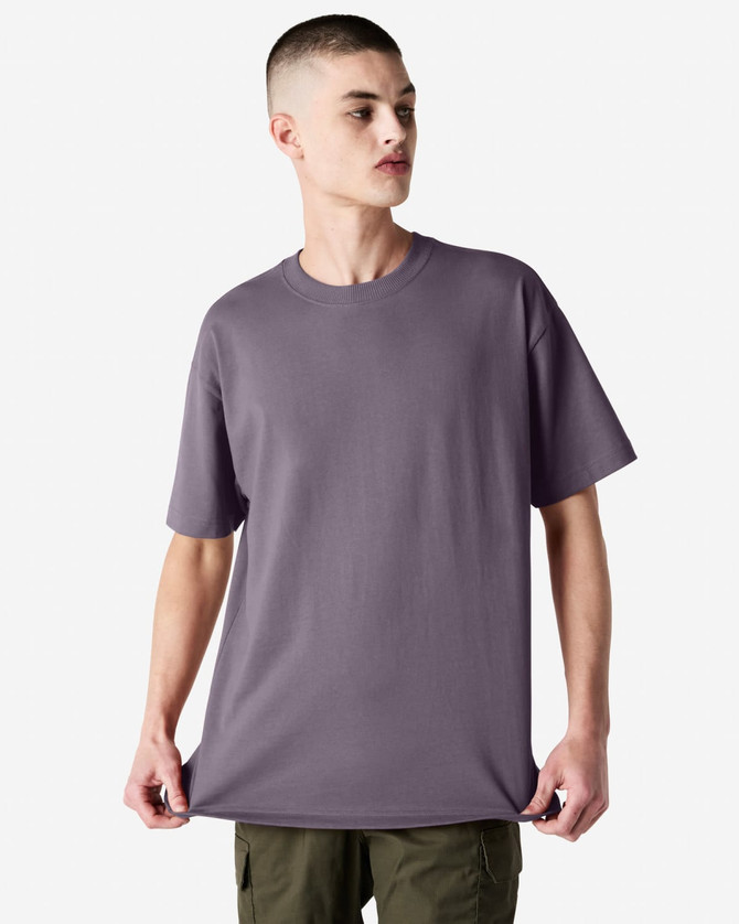 A model wearing a purple American Apparel Super Heavyweight T-Shirt, featuring short sleeves and a relaxed fit.