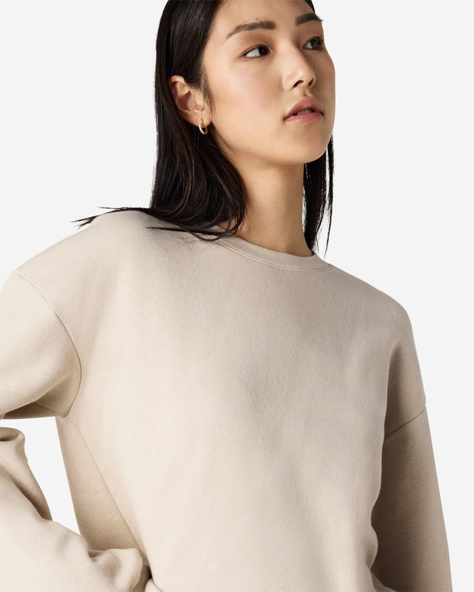 A women's crewneck sweatshirt in a beige colour, featuring a relaxed fit and long sleeves. It has a simple logo.