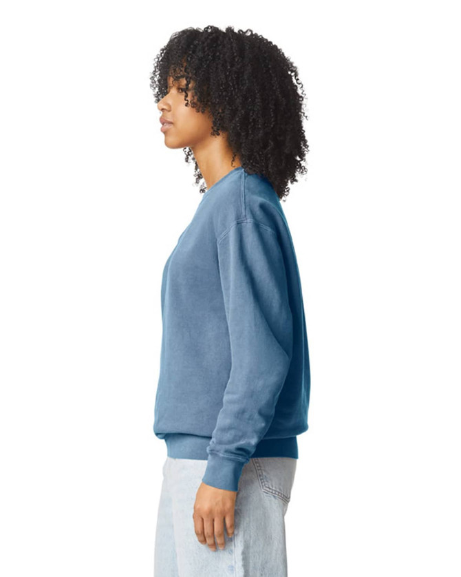 A lightweight crewneck sweatshirt in blue, featuring a logo, worn by a person with curly hair.