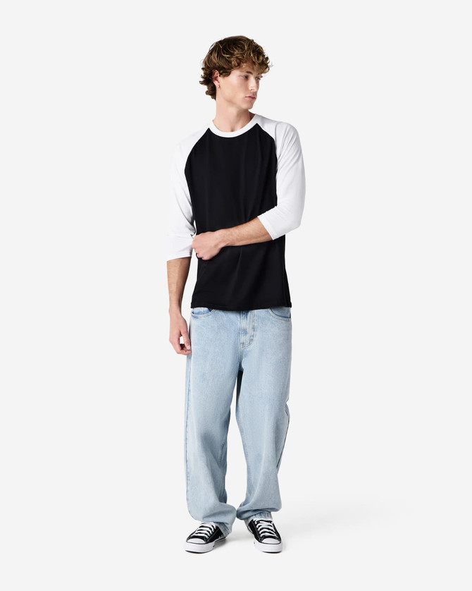 A unisex raglan T-shirt with a black body and white three-quarter sleeves, paired with light blue jeans and black sneakers.