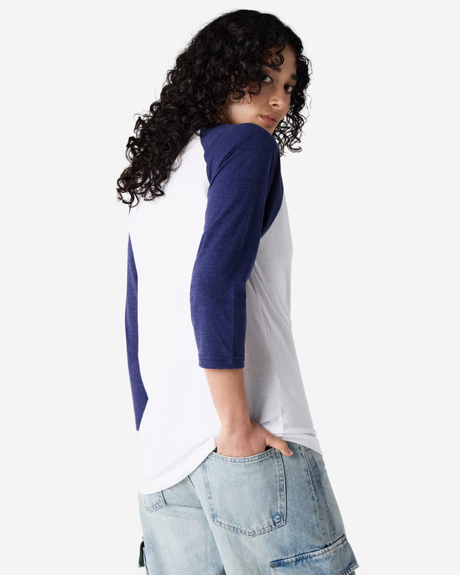 A unisex raglan t-shirt featuring white fabric with navy blue sleeves. The model is posing with a casual look.