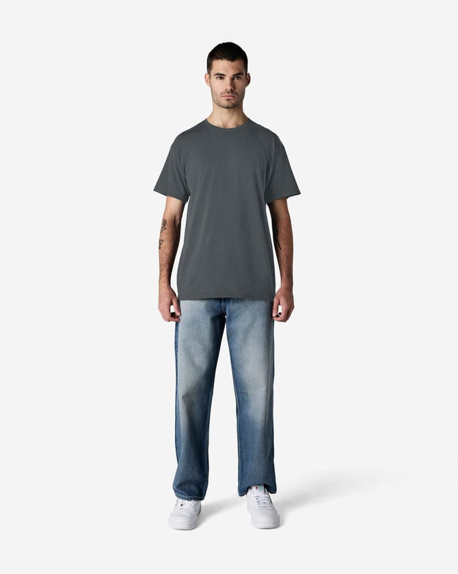A man wearing a grey Gildan Light Cotton T-Shirt and blue jeans, standing against a plain background.