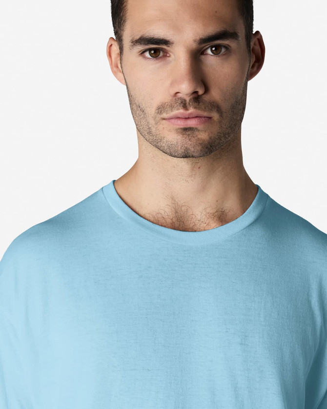 A light blue Gildan Light Cotton T-Shirt displayed on a model, featuring a round neckline and a logo.