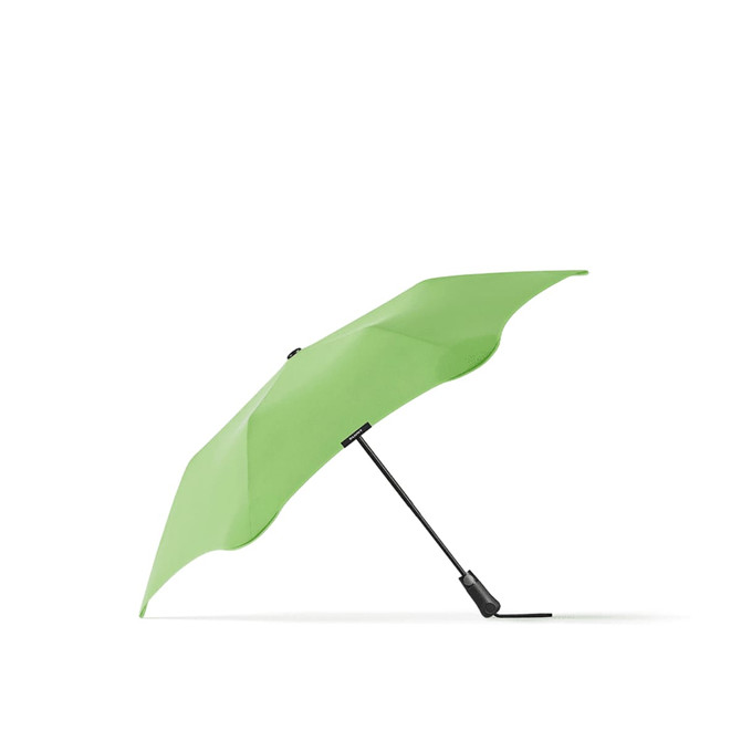A green BLUNT Metro Umbrella with a black handle, showcasing a unique, aerodynamic design.