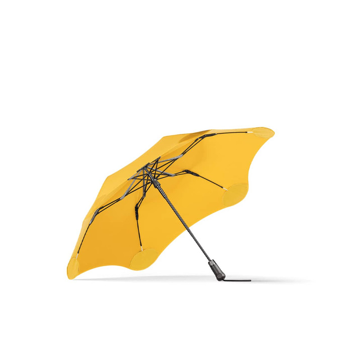 A yellow BLUNT Metro Umbrella with a black frame, featuring a unique, stylish design and a logo.
