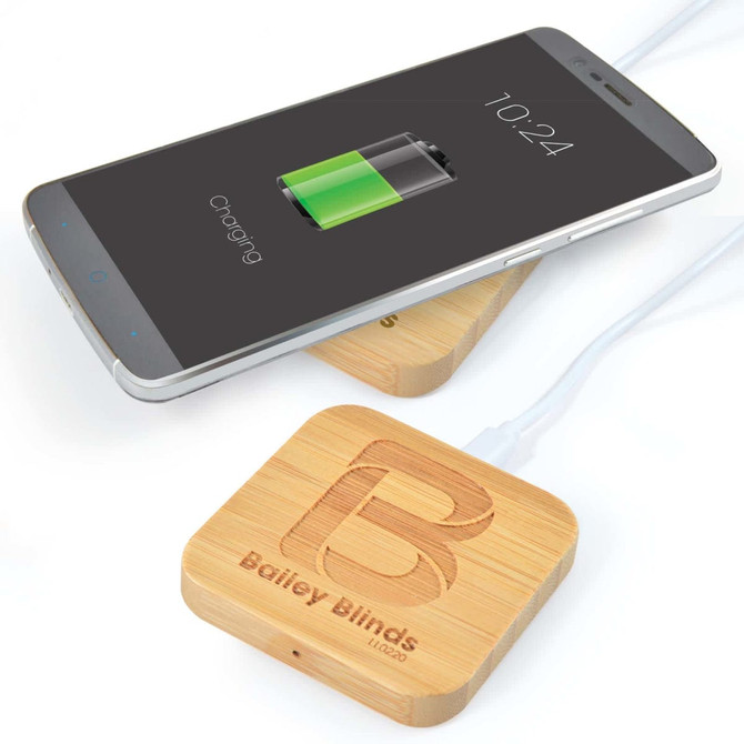 A bamboo wireless charger with a smartphone on top, showing a charging battery icon and featuring a logo.