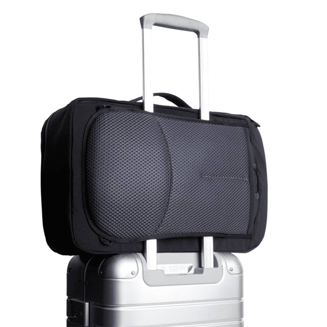 A black Bellroy Lite Travel Pack 30L backpack resting on a silver suitcase, featuring a textured panel and a logo.