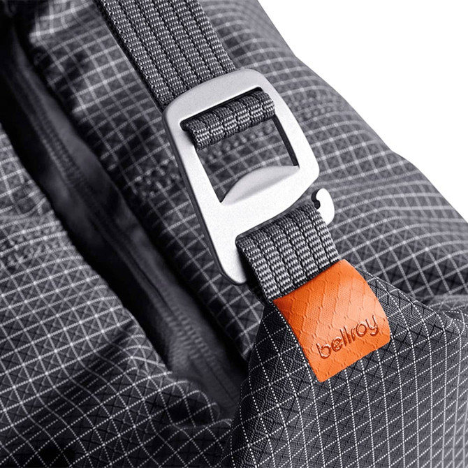 A cooler bag in grey with a silver buckle and an orange tag, featuring a geometric pattern and smooth fabric.