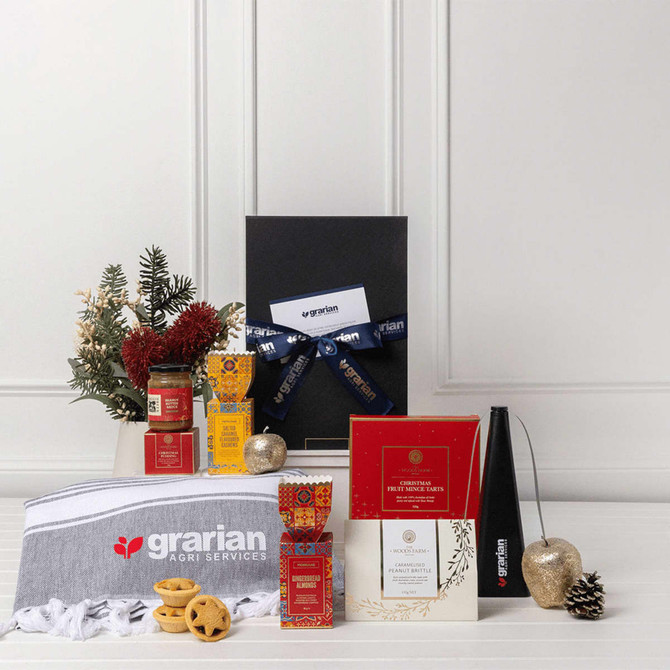 A customised gift set featuring a black box, gourmet treats, a grey towel, and decorative items in red and gold.