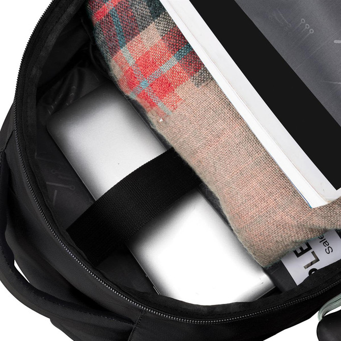 A black backpack interior displaying a laptop, a blanket, and a document. It features an inner logo.