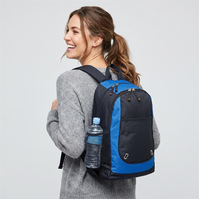 A backpack in black and blue, featuring a drink bottle in a side pocket, worn by a smiling person.