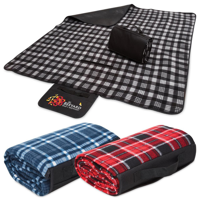 A black and white checkered picnic rug, rolled up with a black strap, alongside blue and red patterned blankets.