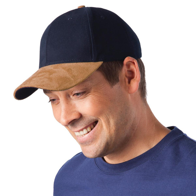 A navy and tan sueded peak cap is worn by a smiling man, featuring a logo on the front.