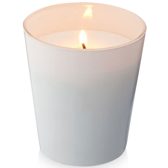 A white scented candle in a glass container, featuring a lit wick, with a soft glow.