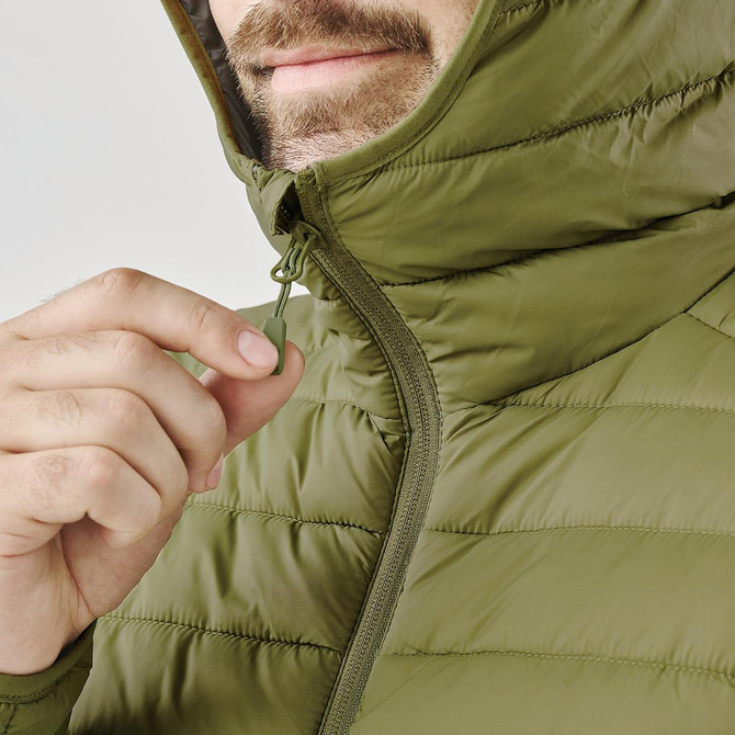 A close-up of a person pulling the zipper on a green thermal jacket, featuring a hood and quilted design.