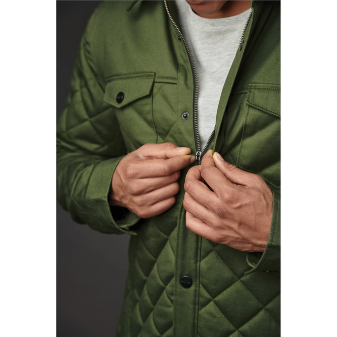 A green quilted jacket with a zip and button closures, featuring chest pockets and a close-up of hands zipping it up.