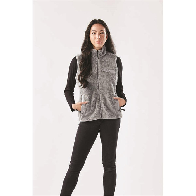 A woman models a grey women's Bergen Sherpa fleece vest, featuring zip pockets and a high collar.