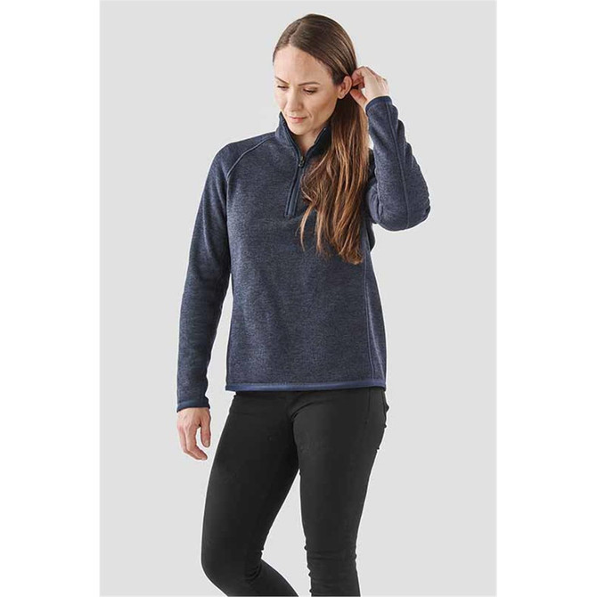 A women's navy blue 1/4 zip pullover, featuring a logo, styled with black pants.