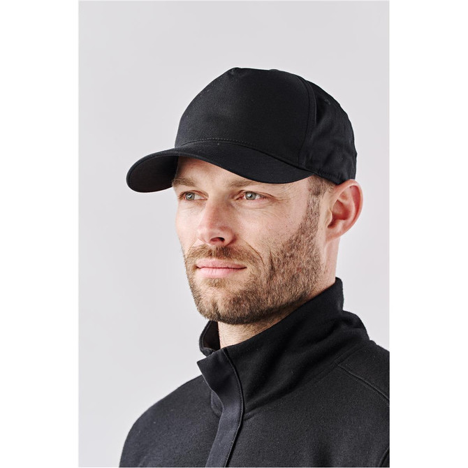 A black cap worn by a man, featuring a curved brim and a fitted design, with a logo on the front.