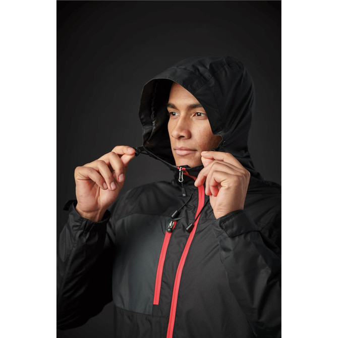 A man in a black rain jacket with a red zipper and hood, adjusting the jacket's neckline. It features a logo.