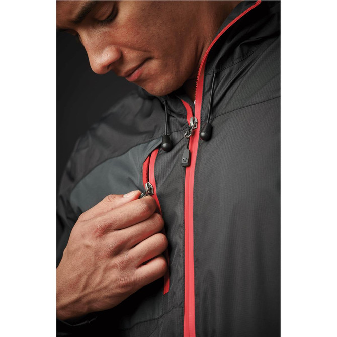 A man in a black rain jacket with red accents, adjusting the zipper near his chest. The jacket features a logo.