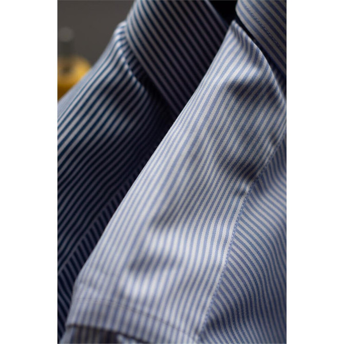 A close-up of a blue and white striped button-up shirt, featuring a folded collar and textured fabric.