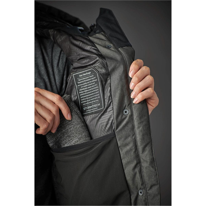 A woman's Oslo HD Parka in dark green, featuring a zipped inner pocket and a logo. 