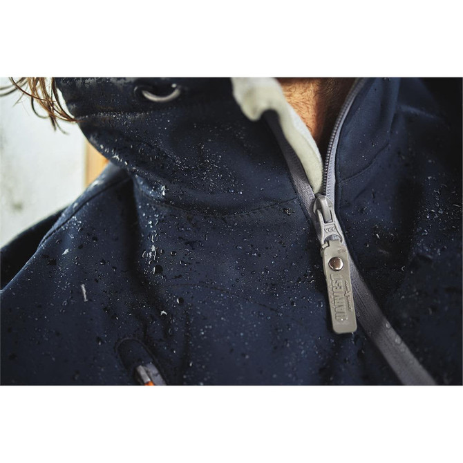 A close-up of a navy softshell jacket with visible water droplets on the fabric and a branded zipper.