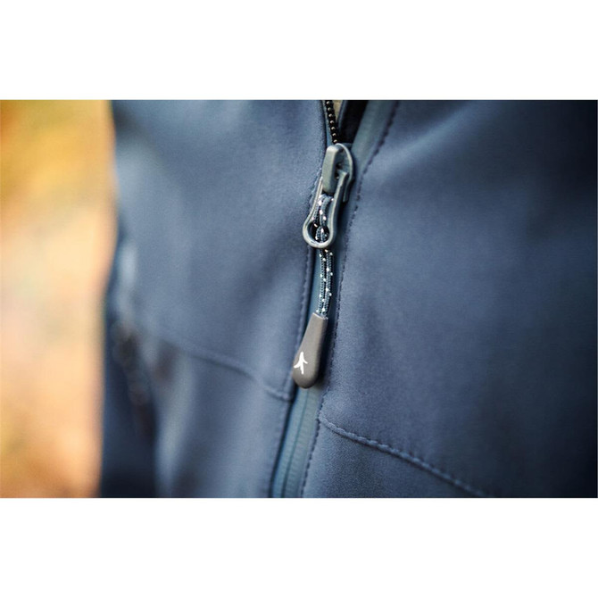 A close-up of a navy blue softshell jacket featuring a zippered front and a logo on the zipper pull.