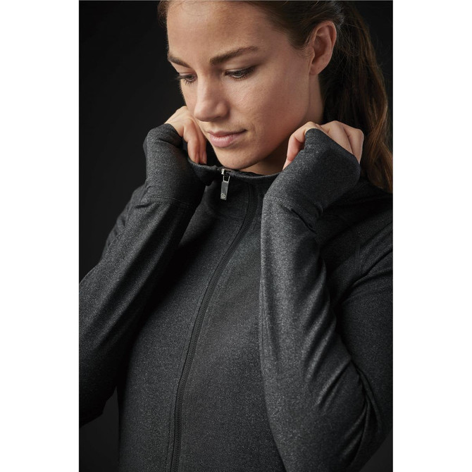 A woman in a black jacket with a zip, featuring long sleeves and a fitted design, looking down thoughtfully.