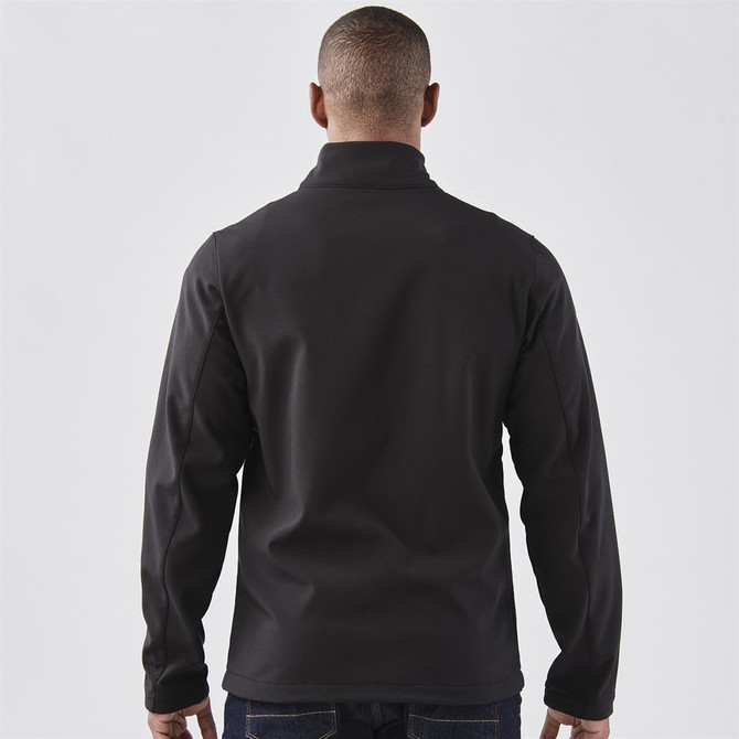 A softshell jacket in black, featuring a stand-up collar, viewed from the back. It has a logo.