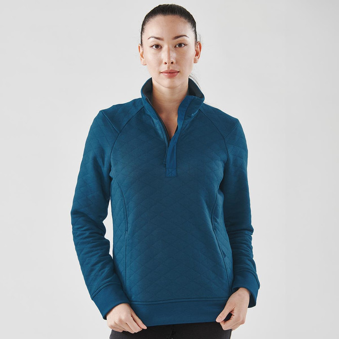 A woman is wearing a teal women's Montebello thermal 1/4 zip pullover, featuring a collar and long sleeves.