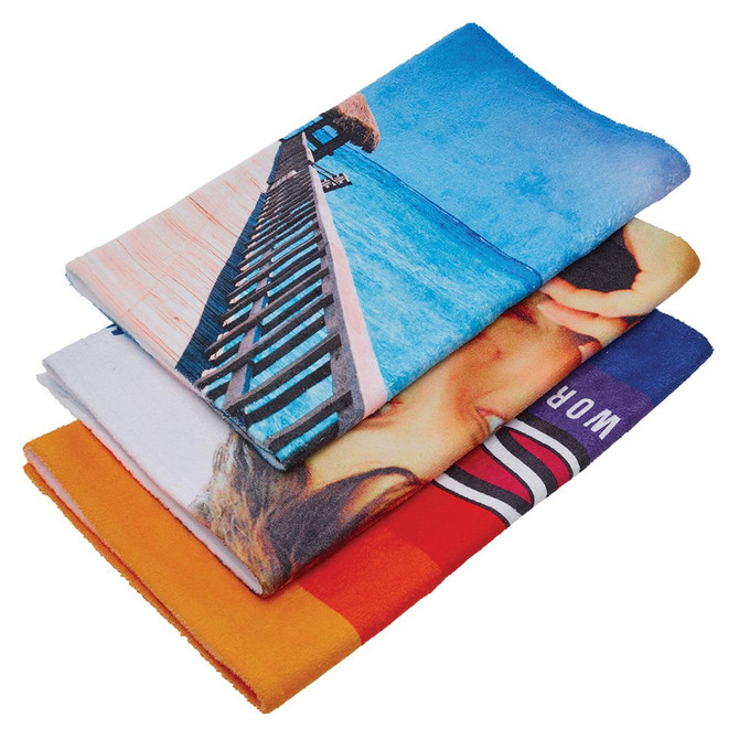 Three sublimation sports towels in vibrant colours, featuring designs of a beach, a sunset, and a model. Each towel is folded neatly.
