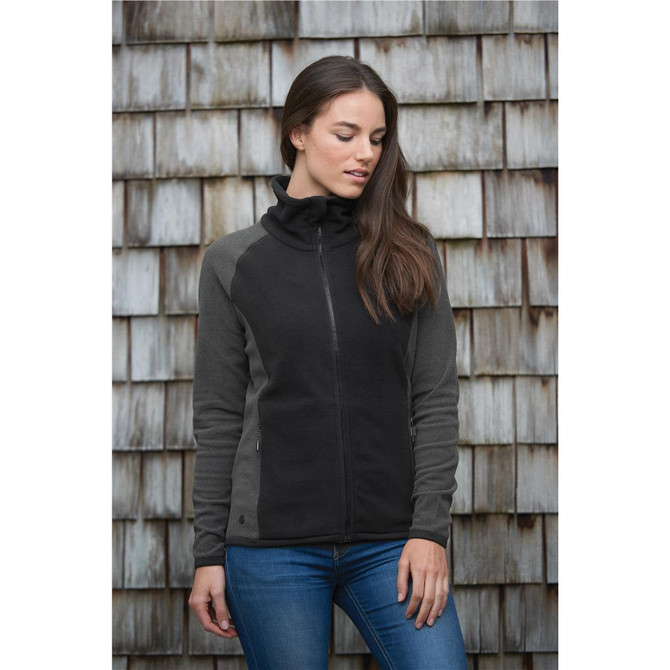 A microfleece jumper in black and grey, featuring a zip front and a high collar, displayed against a wooden background.