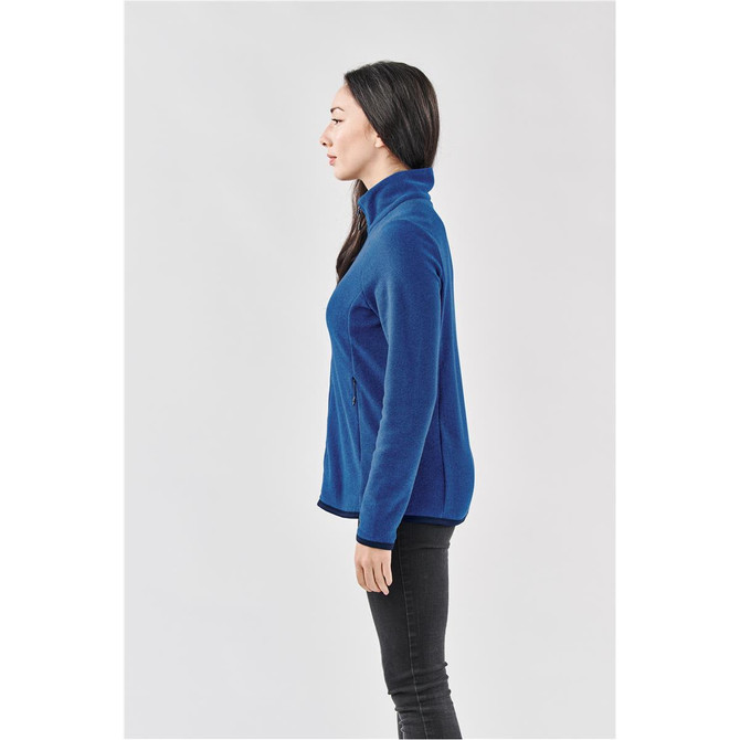 A women's full zip jacket in blue, featuring a high collar and zippered pockets, presented in a side view.