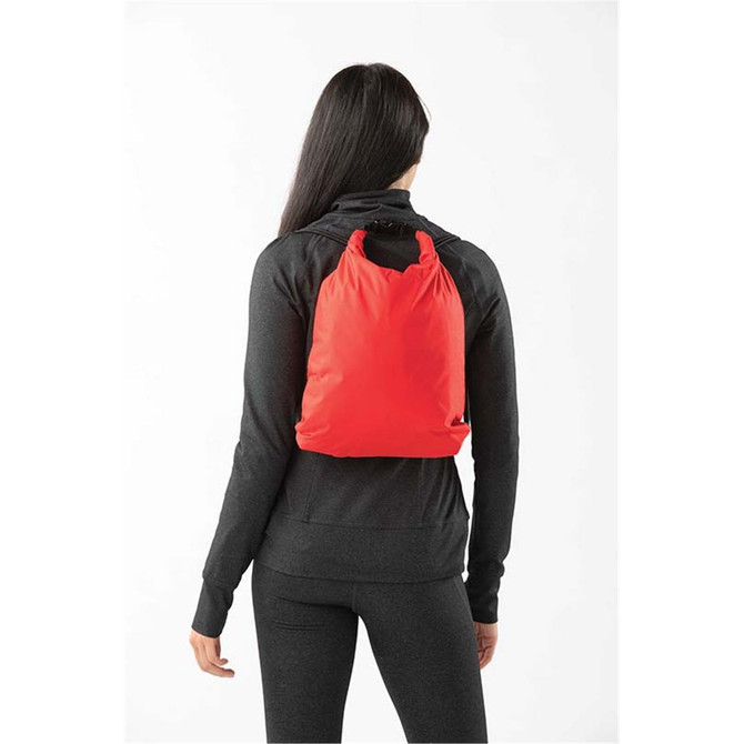 A red drawstring bag is worn on the back of a person dressed in black activewear. The bag has a simple design and features a logo.