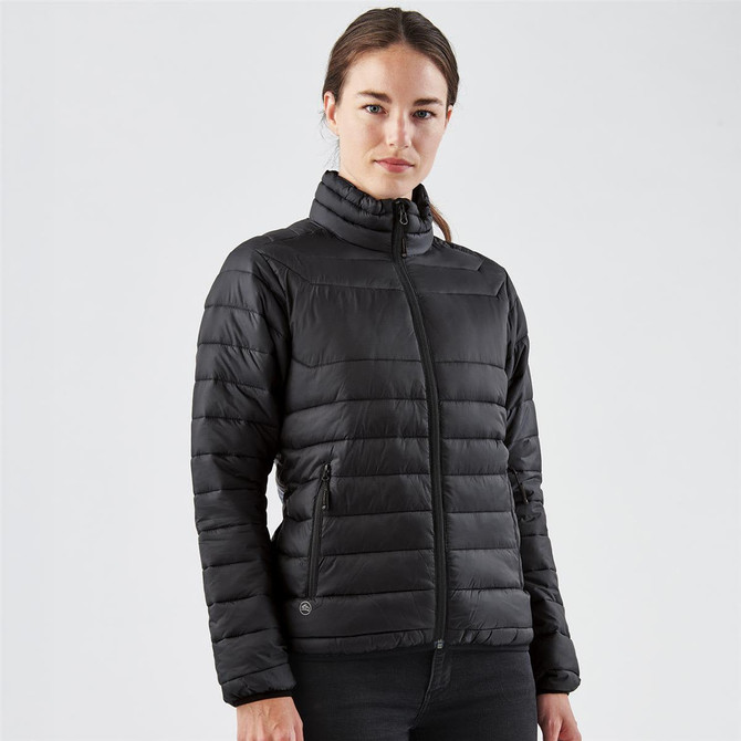 A black women's jacket featuring a quilted design, zip-up front, and high collar. The model is standing against a plain backdrop.