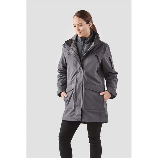 A woman wearing a grey 5-in-1 system jacket with pockets and a zip front, featuring a logo.