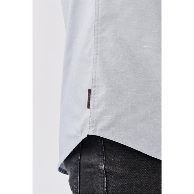 A light grey button-up shirt with a side tag detail, shown from a close-up angle.