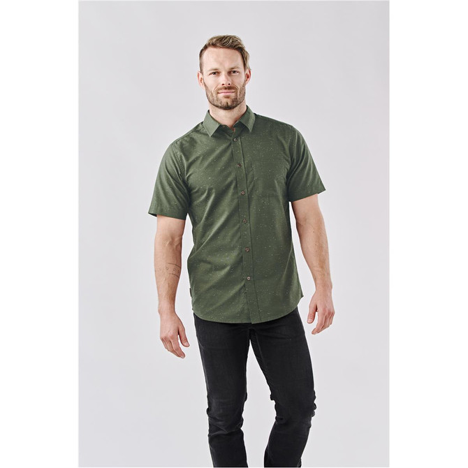 A short-sleeved, green button-up shirt with a subtle pattern, complemented by a model wearing dark jeans.