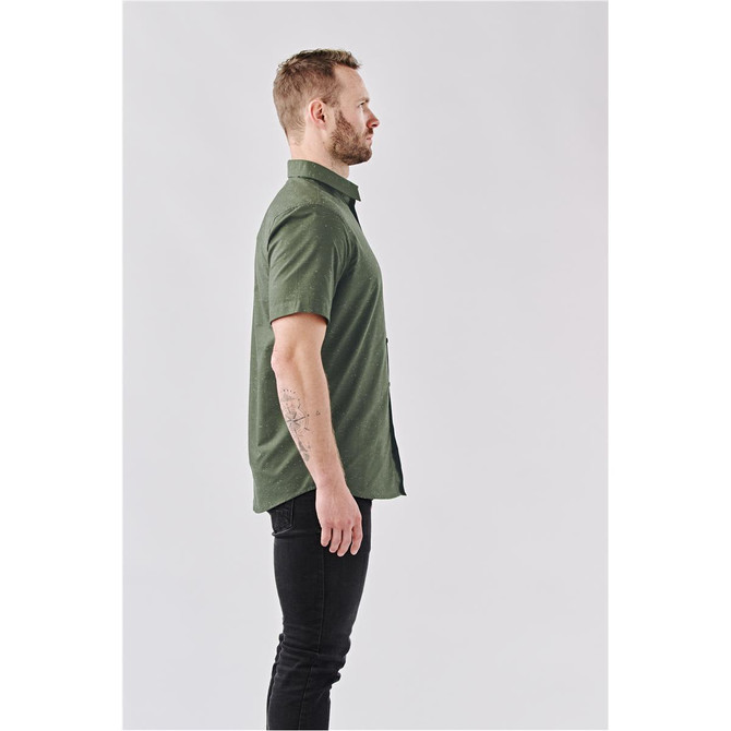 A side view of a man wearing an olive green short-sleeve button-up shirt. The shirt features a logo.