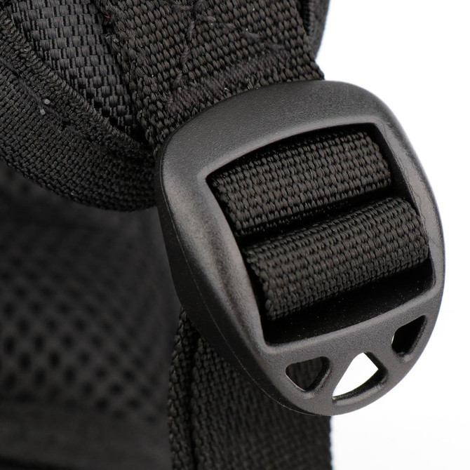 A close-up of a black backpack strap featuring a plastic buckle detail.