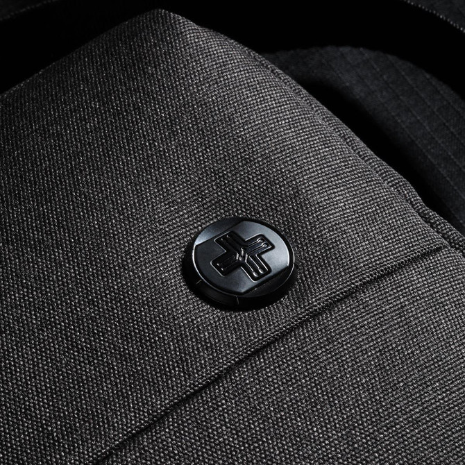 A dark grey shoulder bag with a textured fabric and a logo button. Ideal for carrying laptops and other essentials.