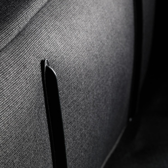 A close-up of fabric showing a textured black surface with a black trim detail. The material appears durable and structured.