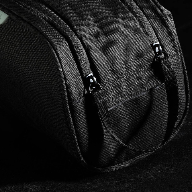 A black toiletry bag with straps and zippers, featuring a textured fabric and branding.